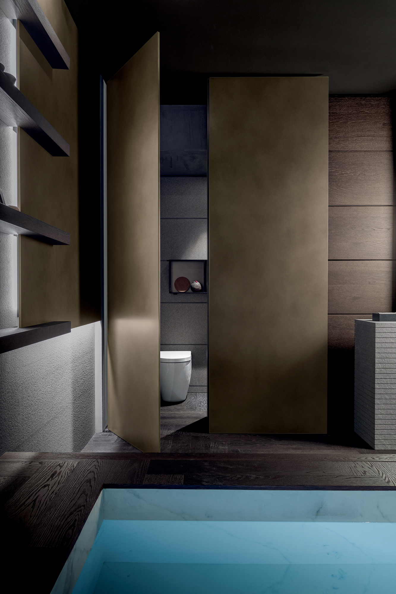 La porta bilico Blade, nella stessa finitura della colonna in metallo Bronze Dust,, attraversa gli spazi inserendosi con naturalezza nel progetto architettonico.